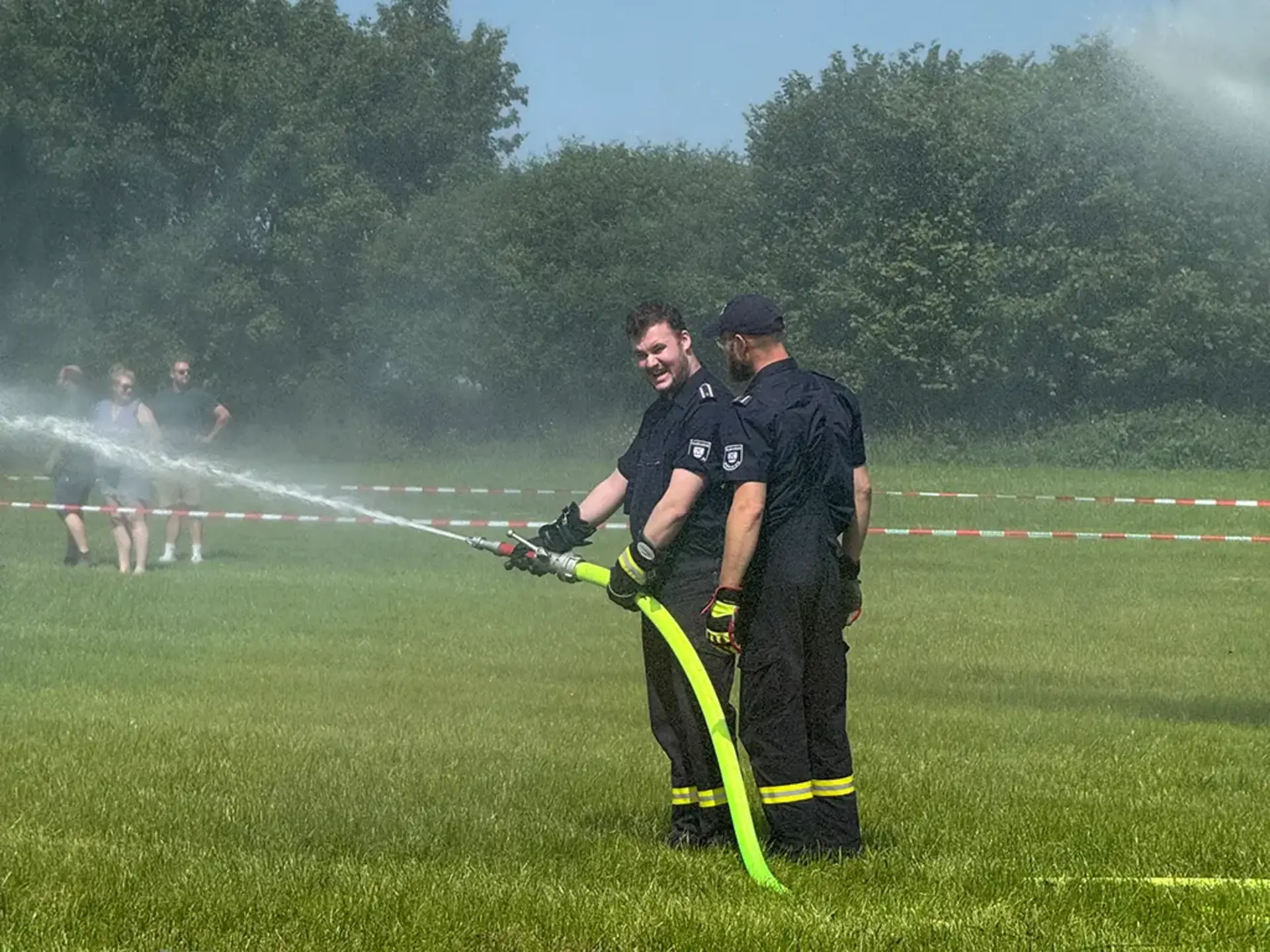 Zwei Feuerwehrmänner halten einen Wasserschlauch